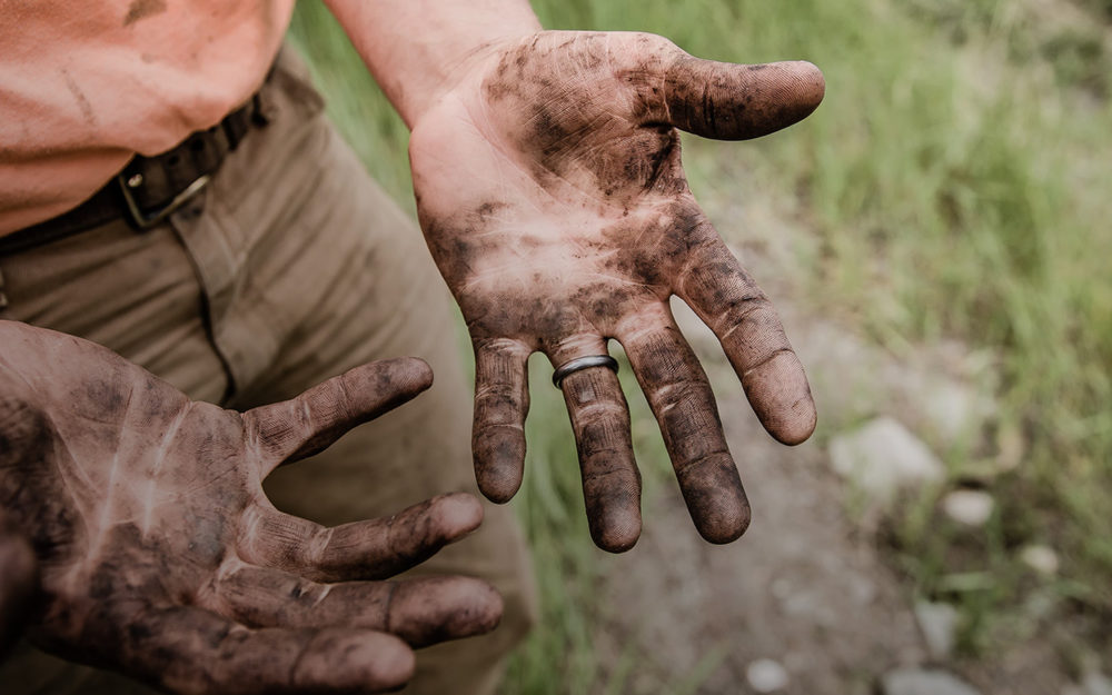 brun jord på beskidte hænder i naturen
